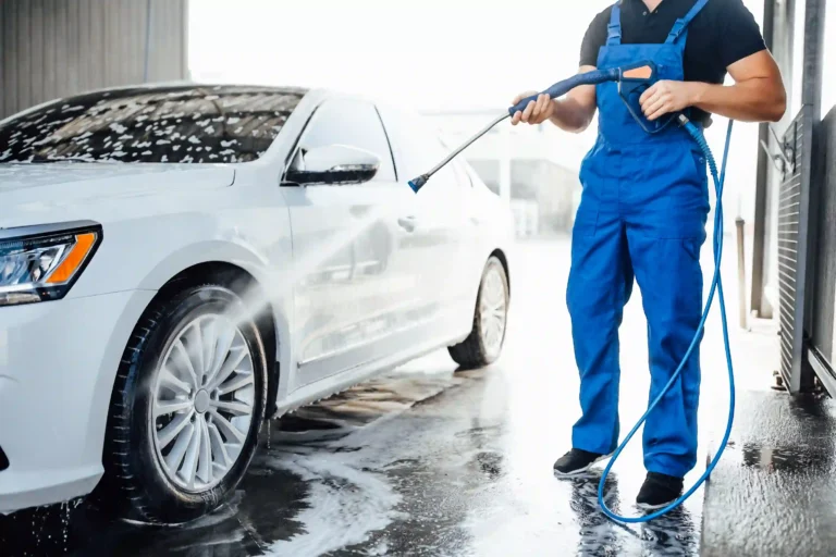 professional-washer-blue-uniform-washing-luxury-car-with-water-gun-open-air-car-wash